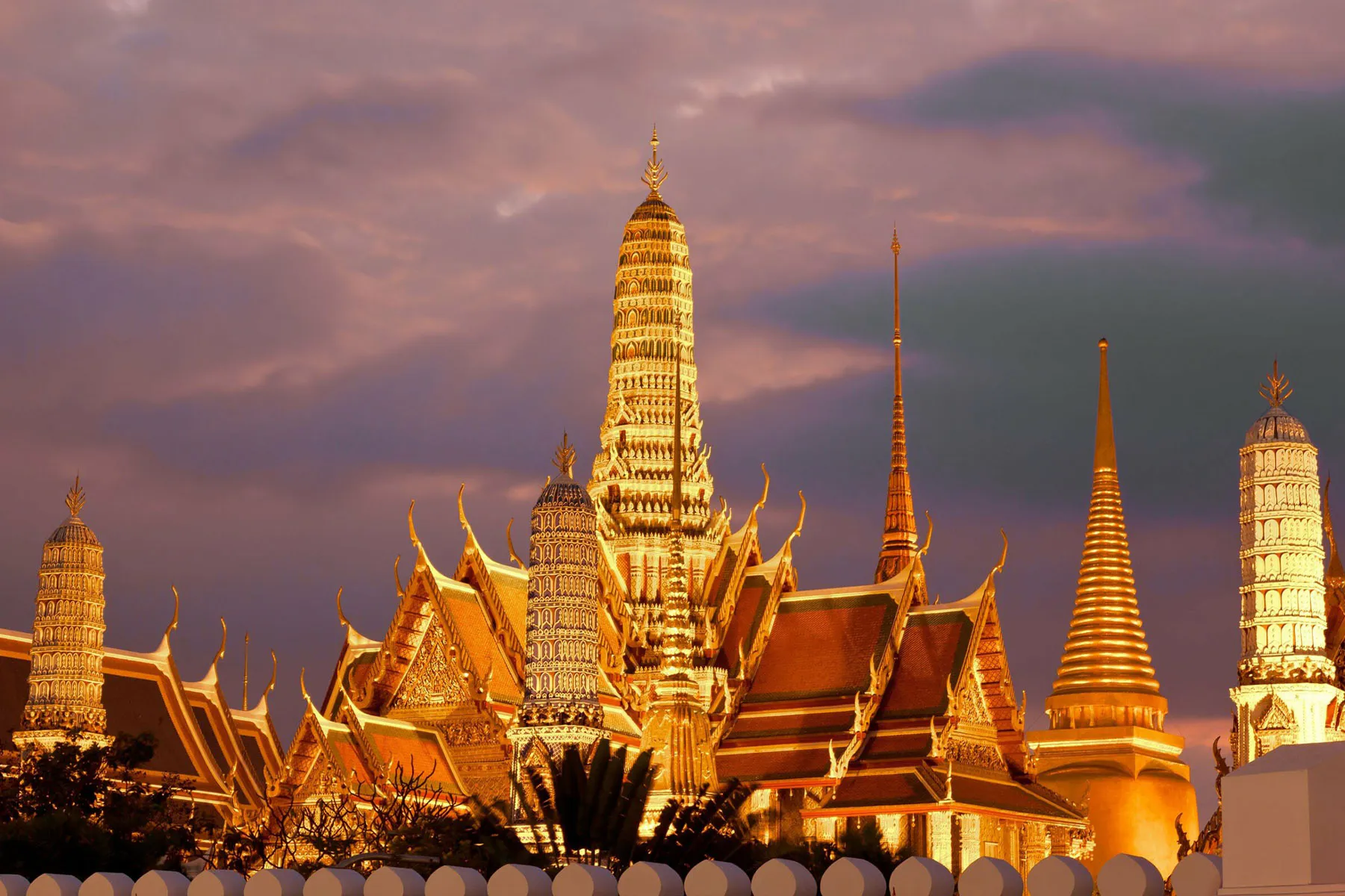 Grand Palace and Wat Phra Kaew spires glowing at dusk in Bangkok