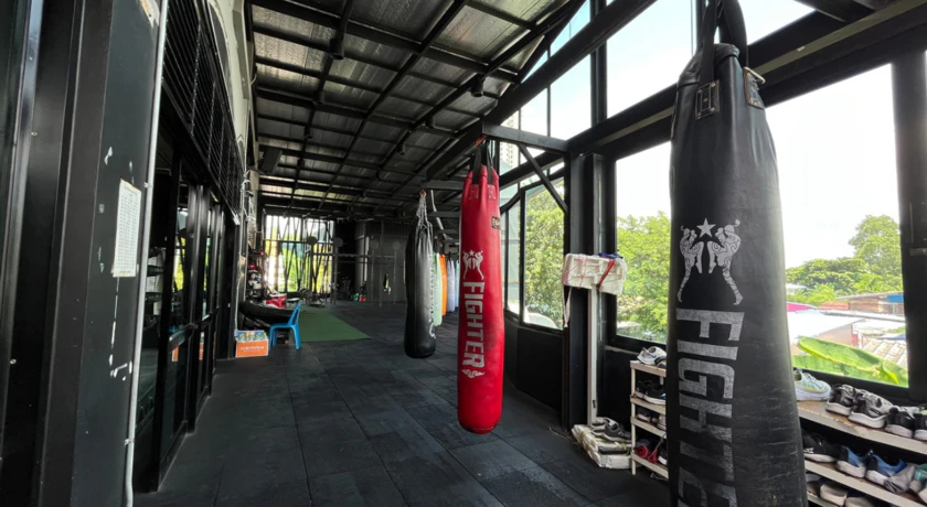 Heavy bags hanging in the open-air training hall at Petchyindee Academy