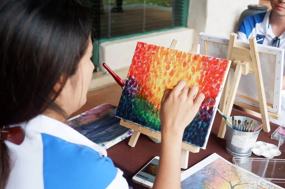 Participant painting a colourful canvas in an art workshop