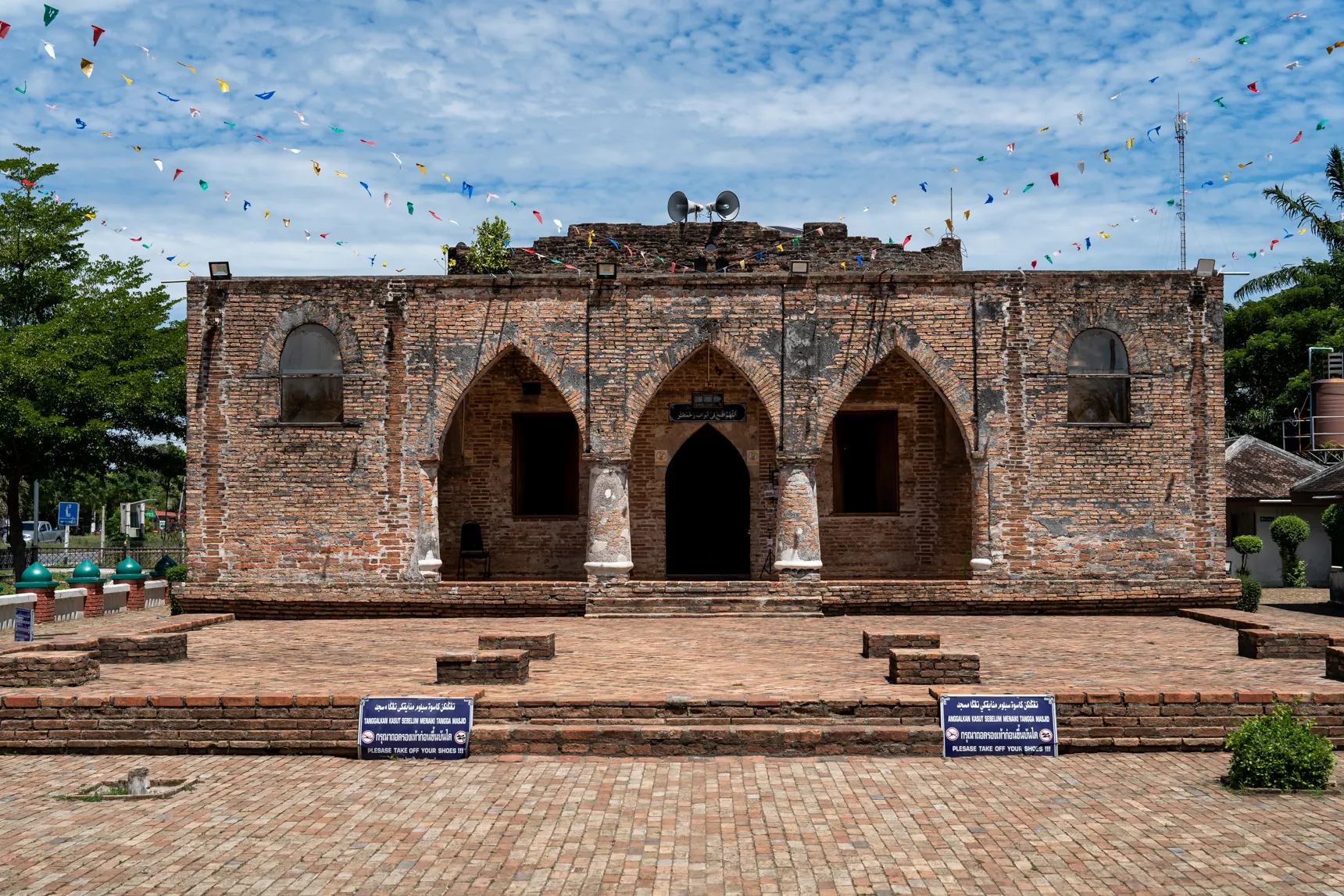 Historic brick mosque façade with festive bunting in Southern Thailand